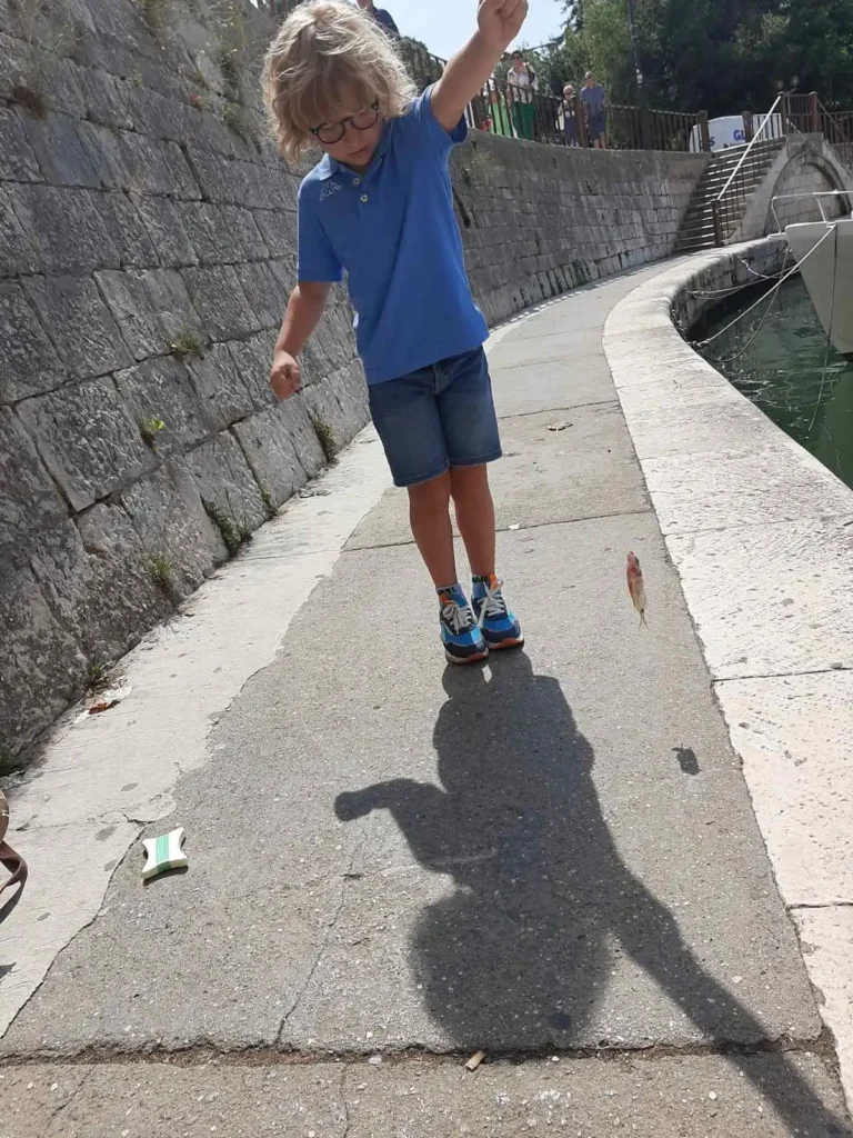 Dječak u ruci drži najlon na kojem je njegova prva ulovljena riba s obale u Zadru. Uživa u trenutku s tunjicom Ižanka.